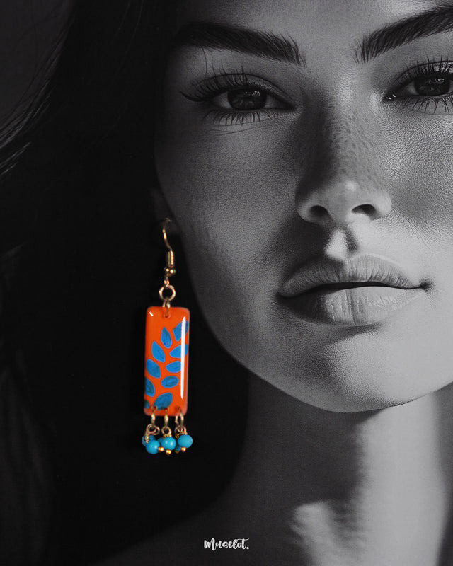 A close-up shot of a model wearing handmade hook earrings, highlighting the intricate floral patterns and handcrafted textures that bring out the artisanal charm and vibrant elegance — Muselot.