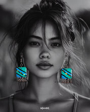A woman models the Jaltarang strip drop earrings, featuring vertical blue and green hand-painted enamel strips with delicate silver ghungroos swaying at the ends, creating a playful yet elegant statement—Muselot.