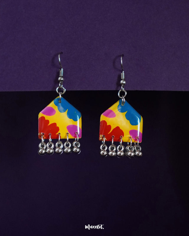 Jharokhe multicolor floral earrings displayed on a deep purple background, featuring vibrant petal patterns in red, blue, pink, and yellow with playful silver ghungroo detailing for a bold, joyful finish — Muselot.