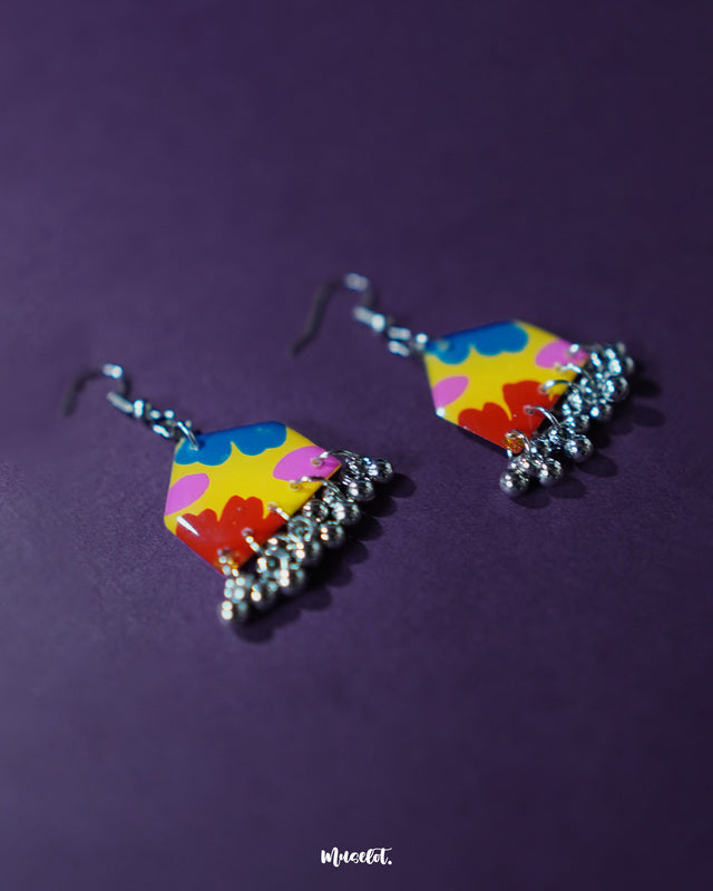 Jharokhe multicolor floral hook earrings laid flat on a purple backdrop, highlighting the hand-painted floral design and intricate craftsmanship that brings out their bohemian charm — Muselot.