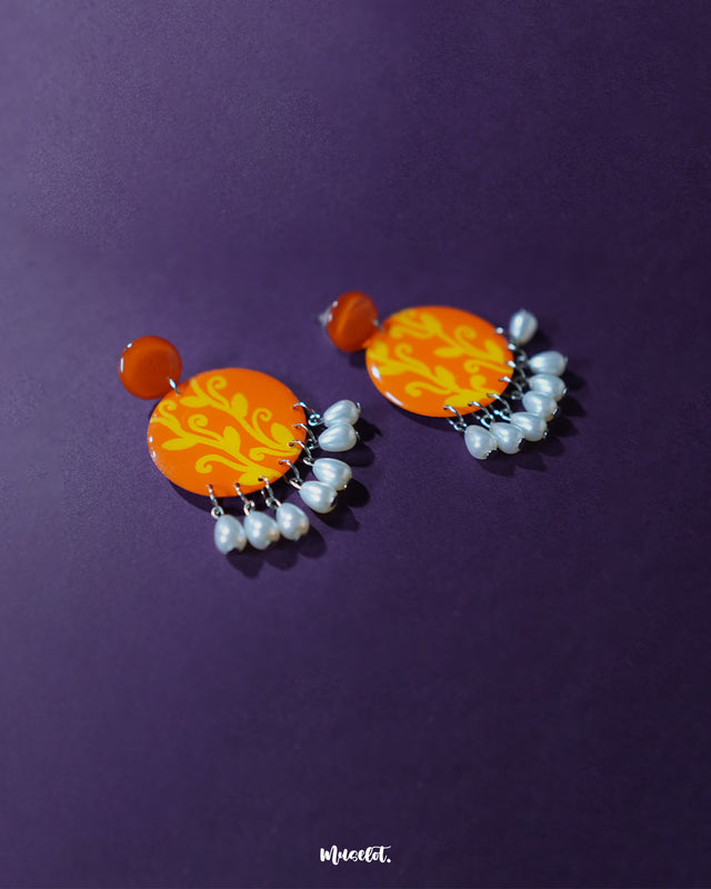 The Kesarbaan orange and yellow drop earrings feature a delicate combination of floral motifs and pearl accents, radiating warmth and charm — a perfect complement to festive or ethnic looks — Muselot.
