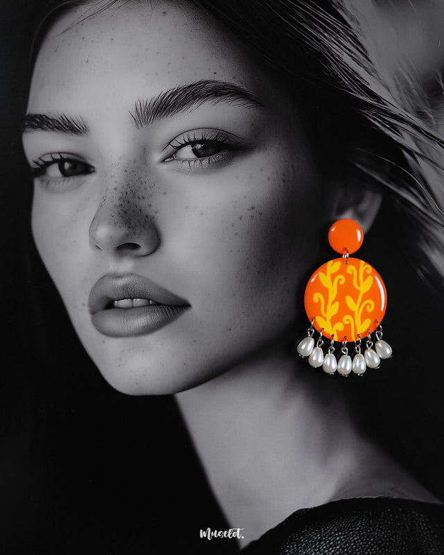 A woman showcases the Kesarbaan pearl drop earrings with effortless elegance—the bold orange-yellow design brings a burst of festive color, while the delicate white pearls add a timeless touch to her ethnic ensemble – Muselot.
