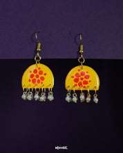 Kesarika floral earrings, set against a soft backdrop, featuring delicate floral patterns and warm tones that bring out a graceful blend of traditional charm and contemporary elegance — Muselot.