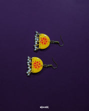 Kesarika floral yellow hook earrings, set against a rich purple background, with vibrant red petals and fine detailing that beautifully contrast with the backdrop, radiating warmth and graceful elegance — Muselot.