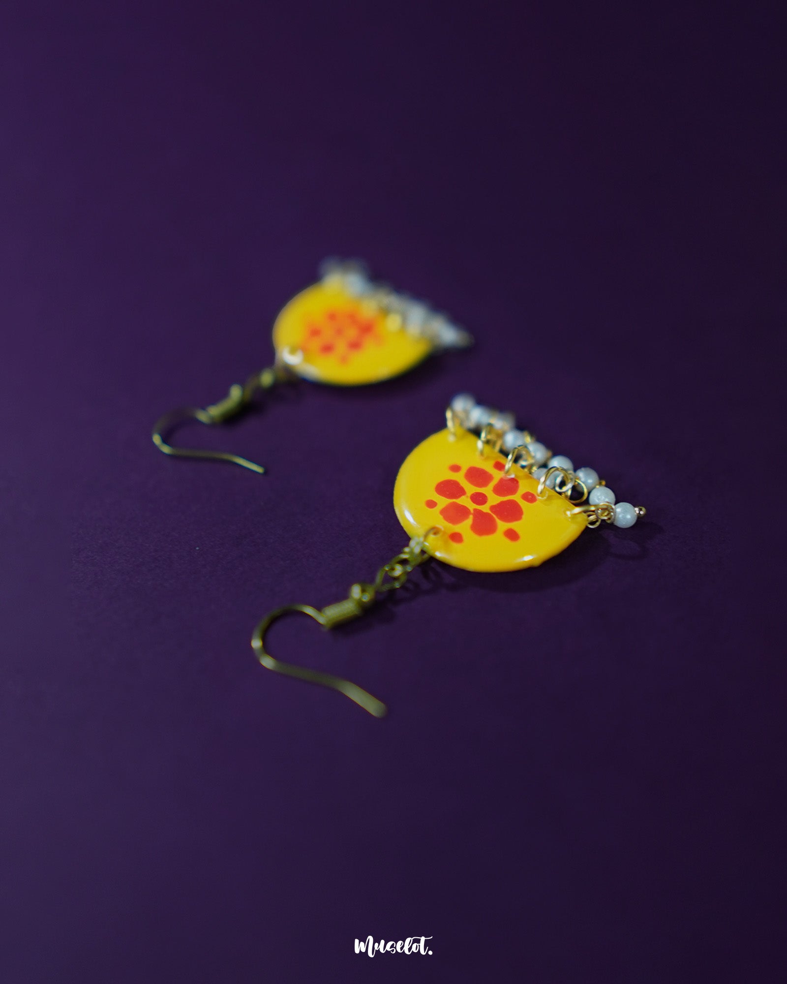 Kesarika floral yellow hook earrings, resting against a deep purple backdrop, featuring bright red floral elements and fine handcrafted details that exude a joyful, vibrant charm — Muselot.