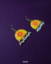 Kesarika floral yellow hook earrings, set against a rich purple background, adorned with striking red floral accents and intricate handcrafted details that add a bold, elegant flair to the design — Muselot.