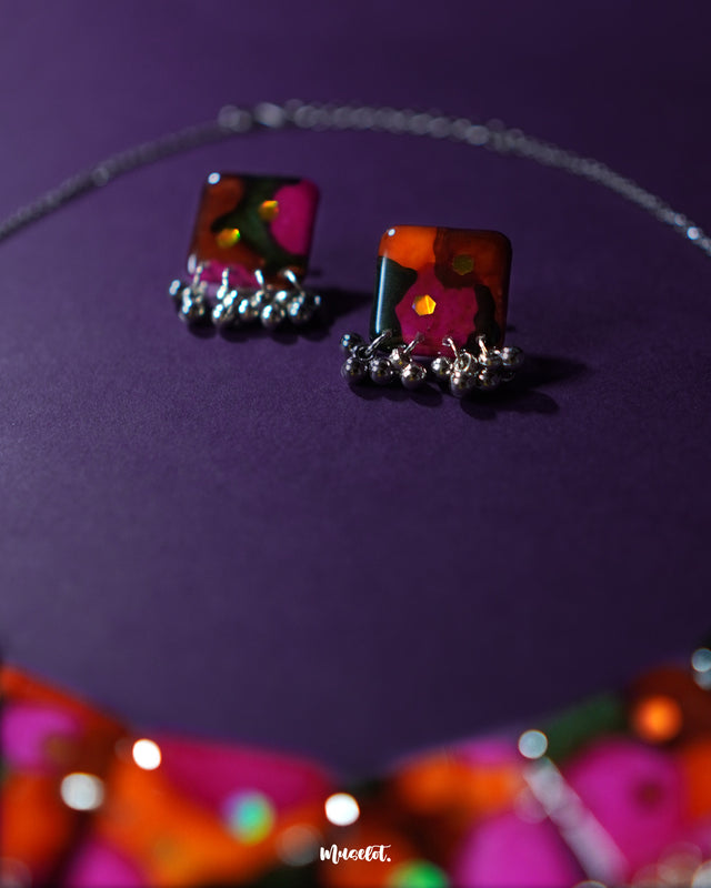 Khushk Gul handmade floral earring featuring a square charm with vibrant pink, orange, and green abstract floral patterns accented by delicate silver beads, beautifully showcased to highlight its intricate design and lively colors – Muselot.