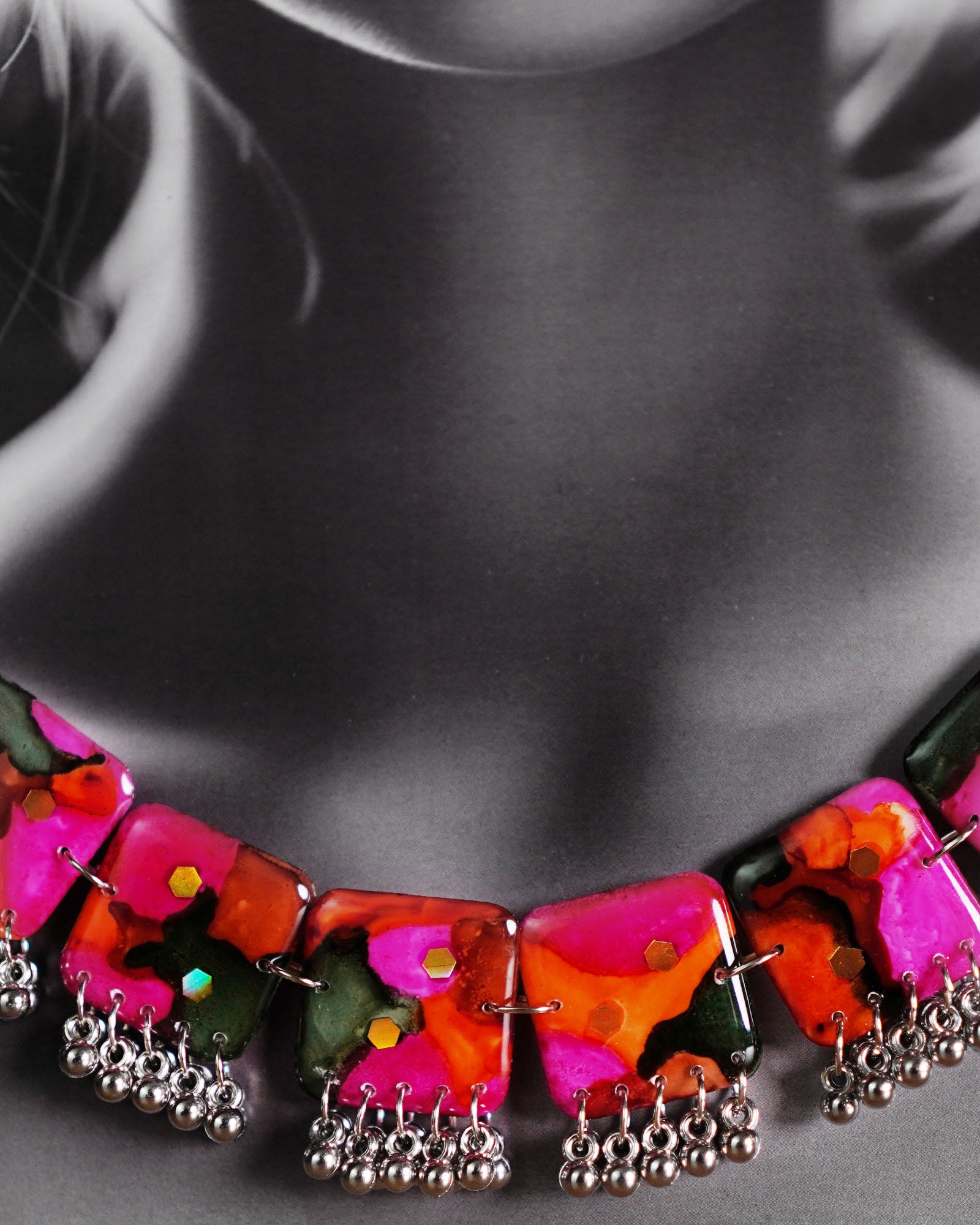 Close-up of model wearing the Khushk Gul handmade floral necklace, showcasing vibrant pink, orange, and green abstract floral-patterned square charms with delicate silver bead accents on a silver chain, highlighting the intricate craftsmanship and vivid colors – Muselot.