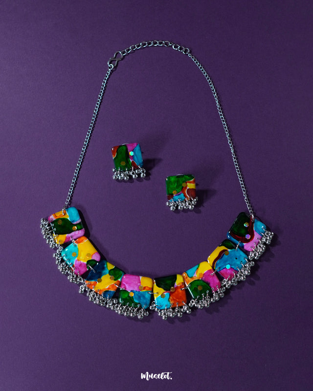 A vibrant multicolor boho necklace set from Muselot, laid out against a deep purple background. The set features bold, beaded detailing with an eclectic mix of colors and textures, highlighting its artistic and statement-making charm — Muselot
