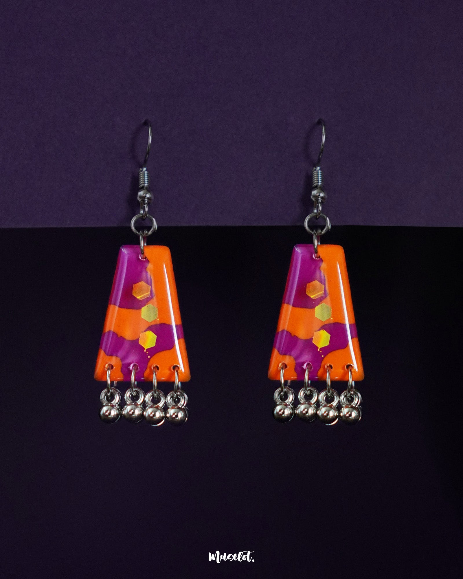 Laalsavera drop earrings against a bold purple background, highlighting their rich red tones and artistic curves that bring a dramatic, statement-making charm – Muselot