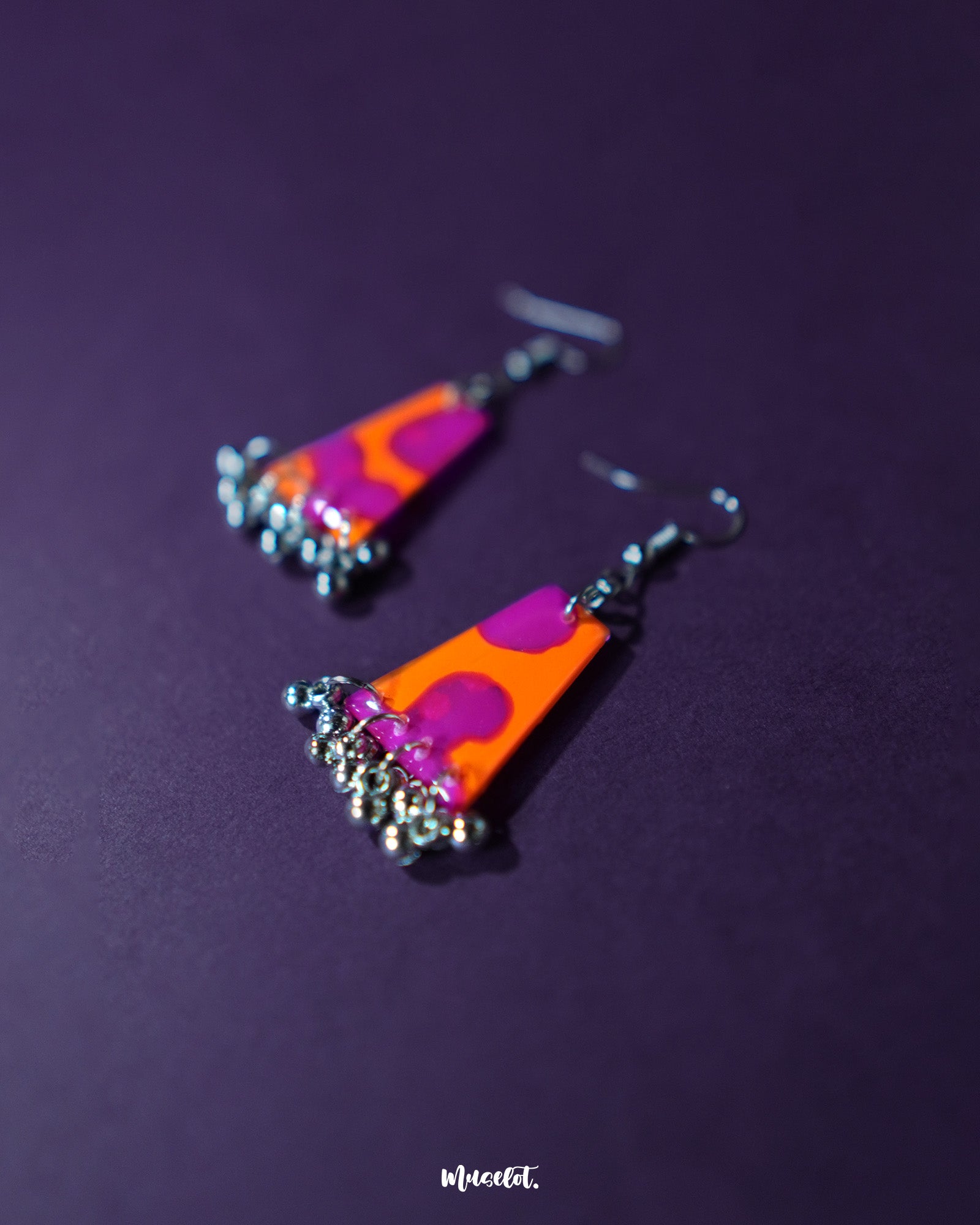 The Laalsavera earrings are placed against a bold purple background, highlighting their abstract charm and rich color tones. Their unique design effortlessly draws the eye, perfect for adding an artistic touch to any look – Muselot