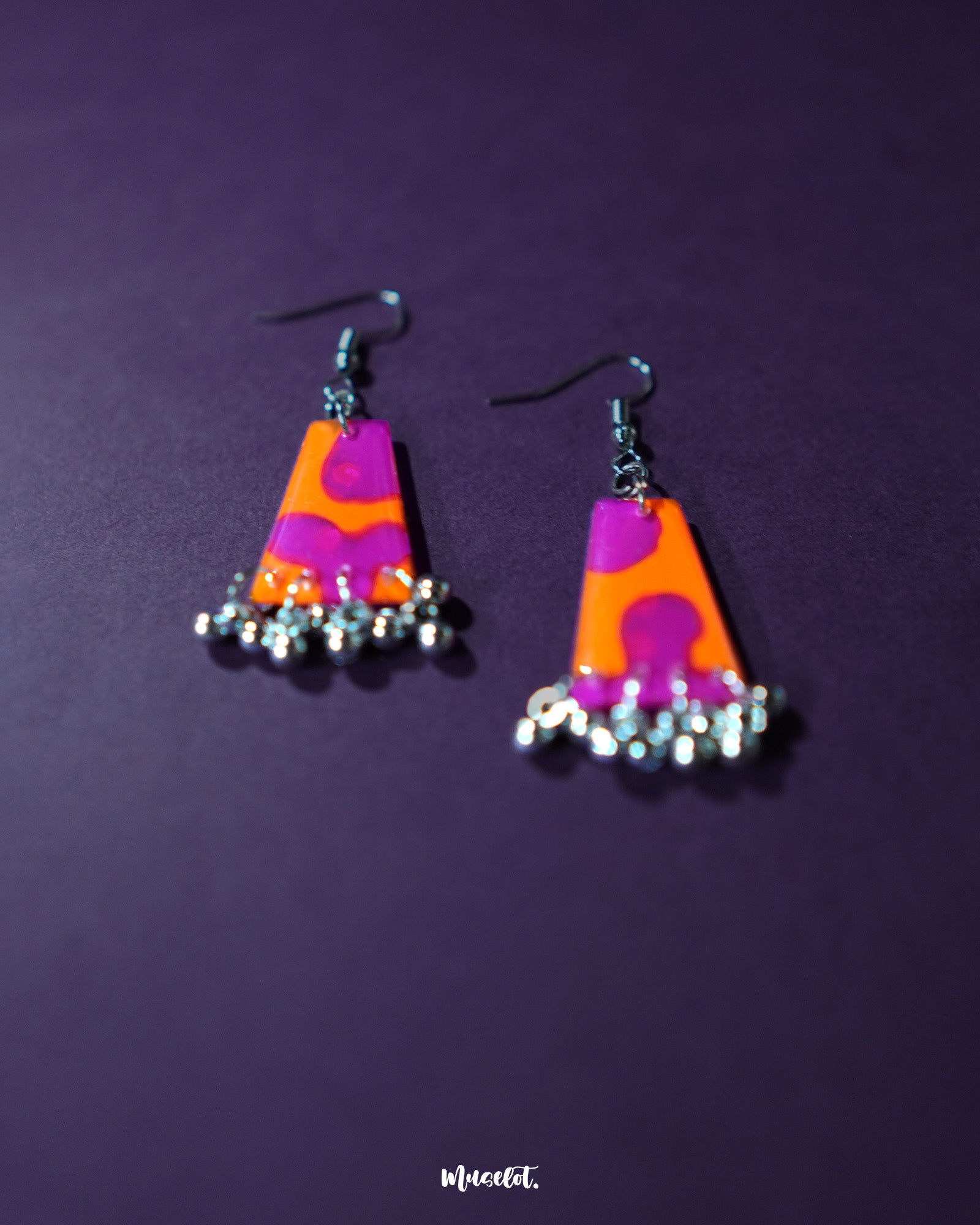 The Laalsavera earrings feature an intricate abstract design that reflects bold individuality, with a rich purple background enhancing their visual appeal – Muselot.