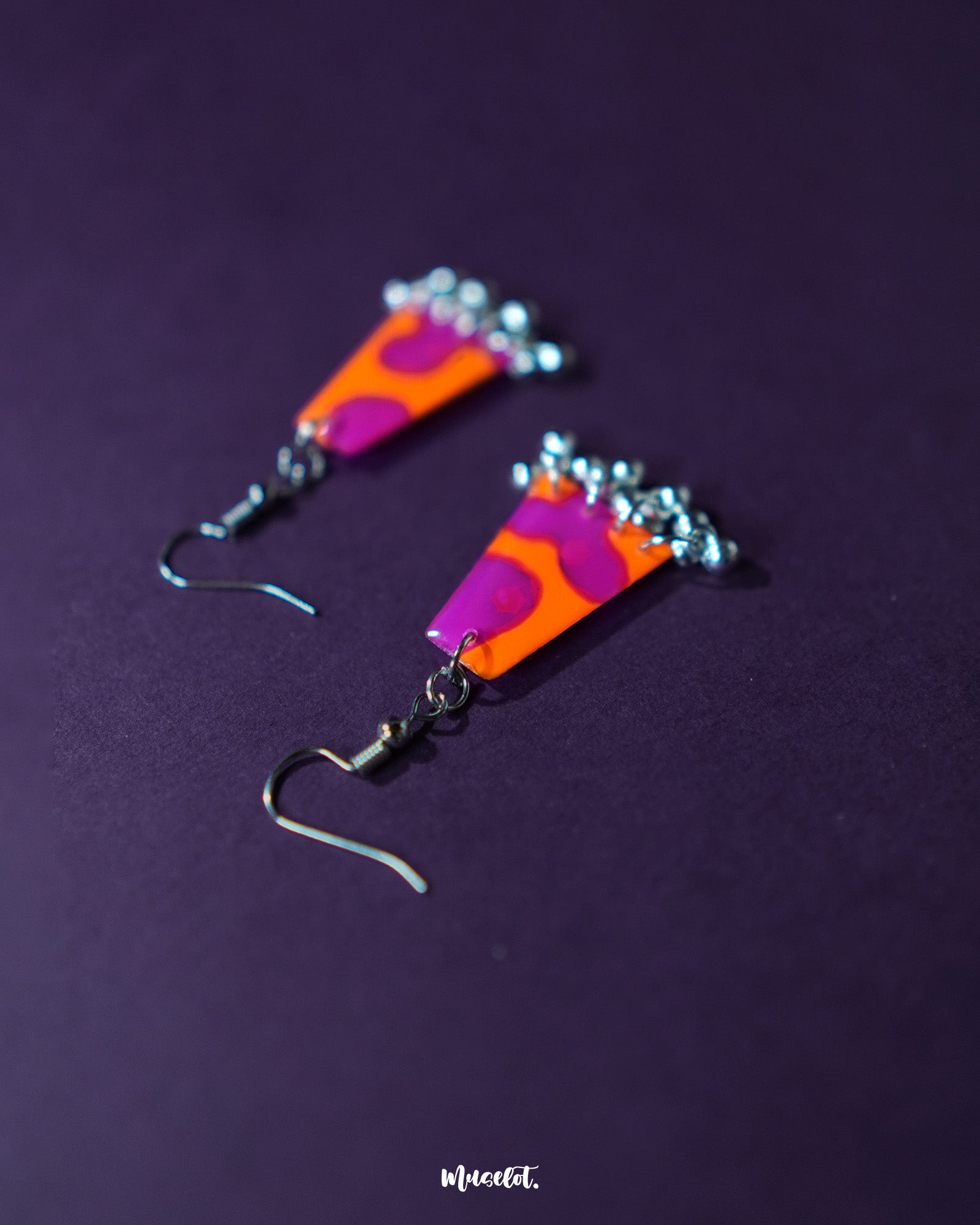The Laalsavera earrings capture attention with their distinctive abstract form, set against a deep purple background that highlights their modern elegance – Muselot.