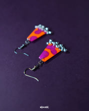 The Laalsavera earrings capture attention with their distinctive abstract form, set against a deep purple background that highlights their modern elegance – Muselot.
