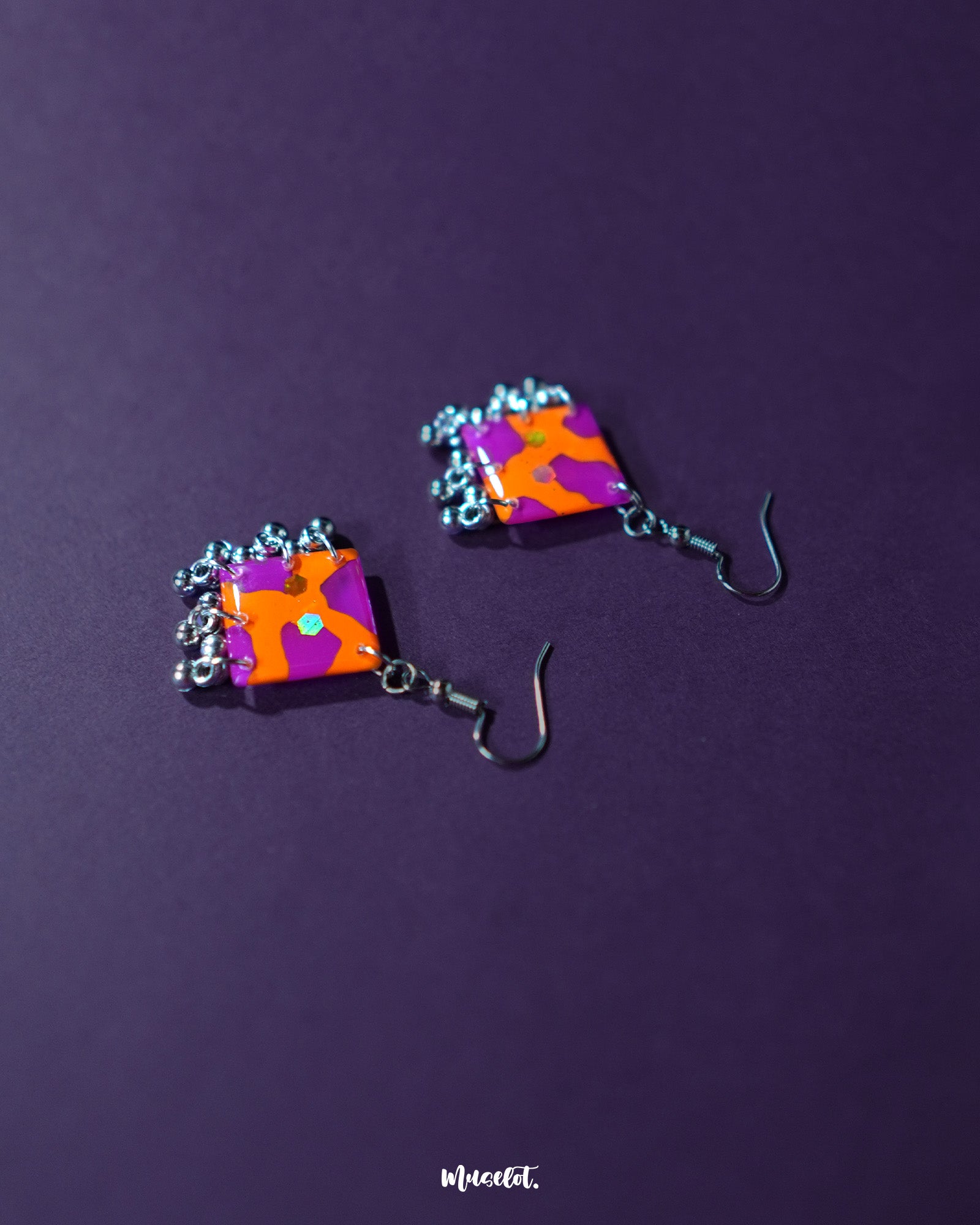 The Laalsavera hook earrings exude charm with their artistic curves, subtly highlighted against a bold purple background — Muselot.