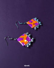 The Laalsavera hook earrings, set against a rich purple background, showcase a refined and modern style-Muselot.