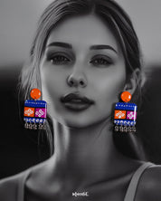 Model wearing the Leheriya boho earrings, featuring bright orange round studs attached to vibrant blue rectangular drops with orange and magenta blocks, decorated with white geometric patterns and dotted detailing, finished with dangling silver beads, highlighting their colorful and eclectic charm – Muselot.