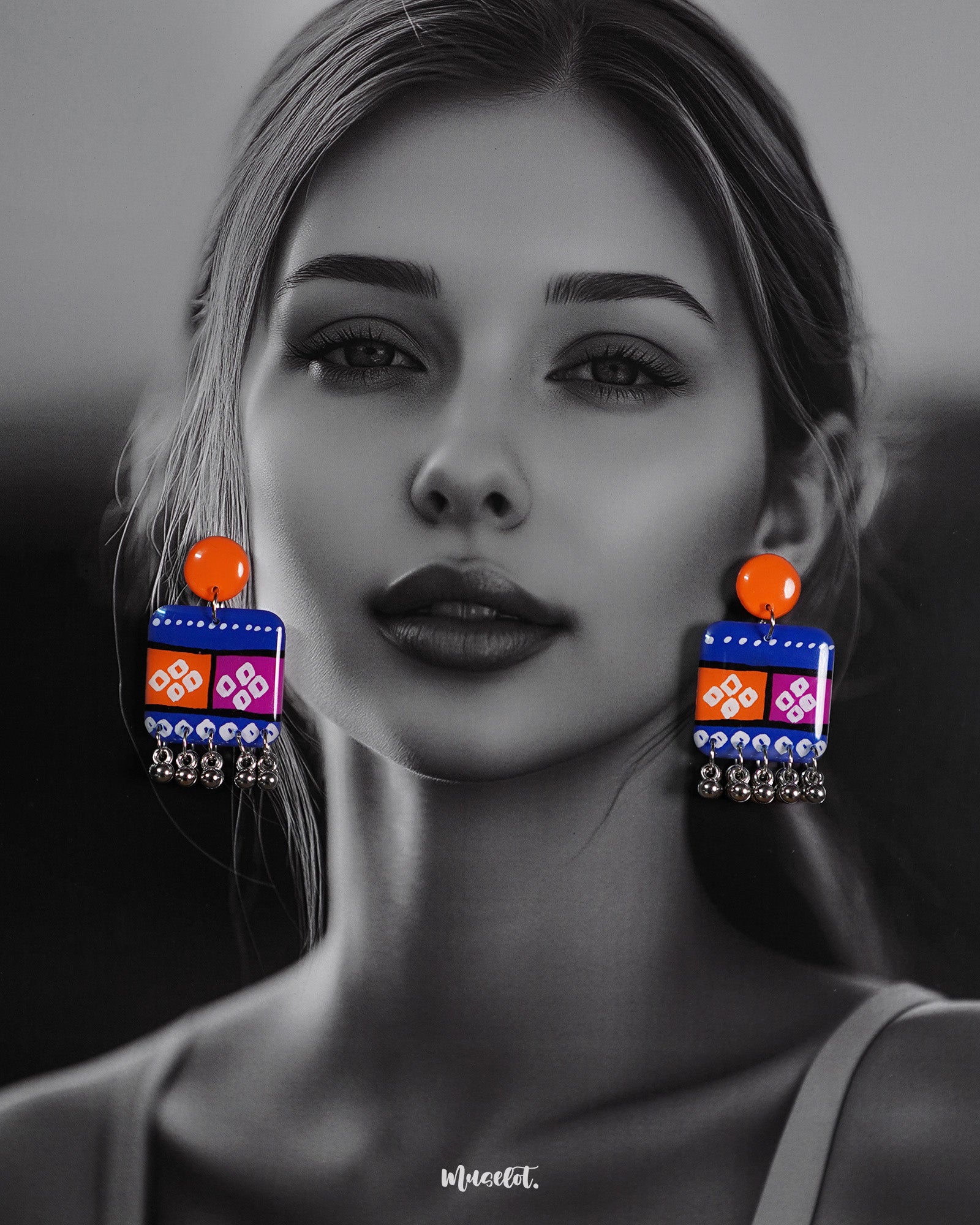 Model wearing the Leheriya boho earrings, featuring bright orange round studs attached to vibrant blue rectangular drops with orange and magenta blocks, decorated with white geometric patterns and dotted detailing, finished with dangling silver beads, highlighting their colorful and eclectic charm – Muselot.