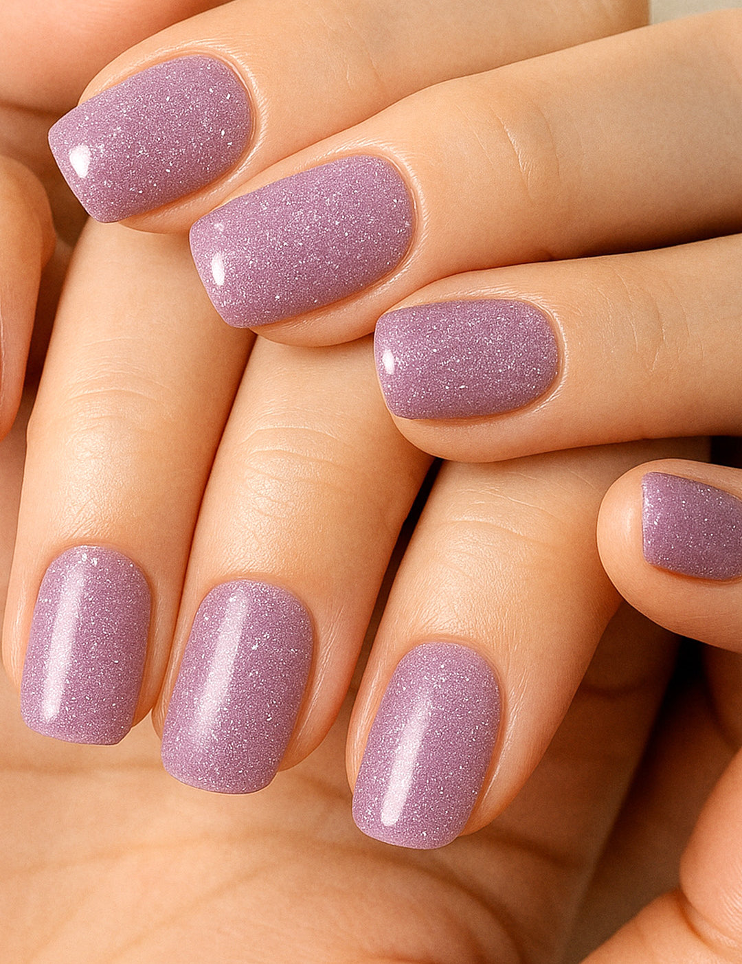 A model’s hand wearing Lilac Dust simple glitter nail stickies, showcasing the pastel lavender shade with delicate sparkles, highlighting its soft glossy shine and adding a chic, minimal yet elegant nail art look – Muselot.