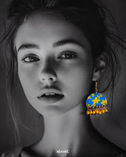 a model wearing Mahrosh blue and yellow hook earrings, with striking blue and yellow tones and intricate design elements that bring a fresh, elegant vibe to the ensemble — Muselot.