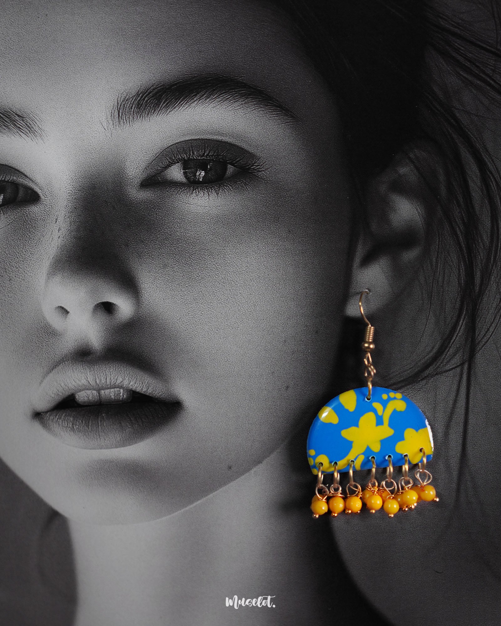 Close-up shot of a model wearing Mahrosh blue and yellow hook earrings, featuring a vibrant blend of blue and yellow hues, with intricate detailing that adds a lively and elegant touch to the overall look — Muselot.