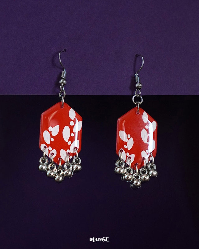 A pair of Mehar red hook earrings featuring a vibrant glossy finish and intricate handcrafted detailing, highlighting their bold, statement-making design and showcasing timeless artisanal charm — Muselot.