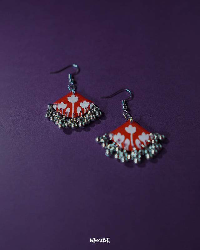 A Meherbaan red floral hook earrings, showcasing their bold red tulip design with silver ghungroos, highlighting the handmade charm and festive elegance — Muselot.
