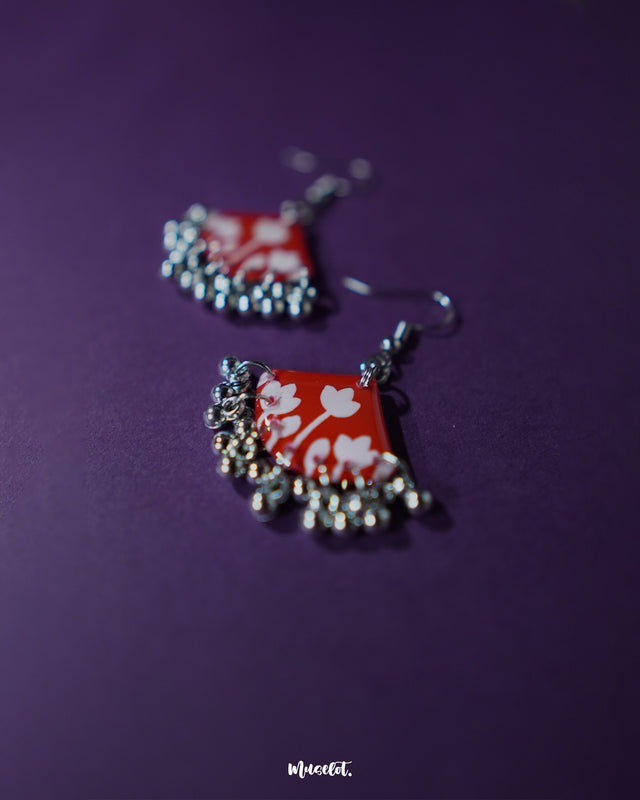 Close-up of Meherbaan red floral hook earrings featuring intricately layered flower petals and tiny hanging beads, highlighting handcrafted finesse and showcasing their statement charm — Muselot.