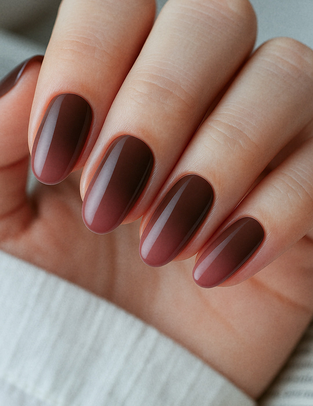 A detailed close-up of a model’s finger's wearing Melted Cocoa brown ombre nail polish stickies, showcasing the smooth gradient that blends from a soft milk-chocolate brown into a deep cocoa shade, highlighting the glossy texture and elegant salon-style ombre finish – Muselot.