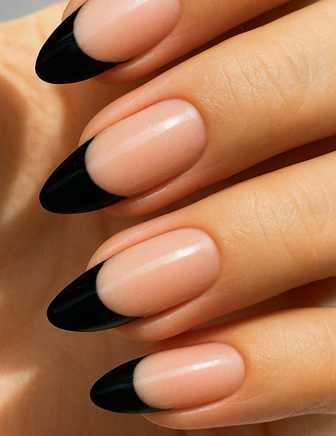 A close-up of a model’s hand wearing Midnight Tiara French Tip nail stickies, featuring a sleek black French tip design over a natural nude base. The glossy finish highlights the sharp contrast, giving a bold yet elegant twist to the classic French manicure style – Muselot.