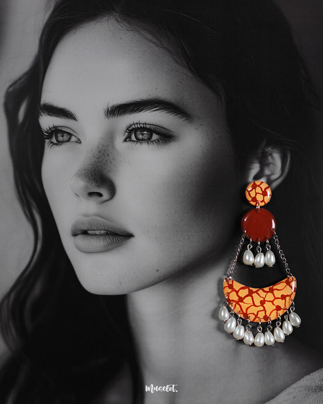 A model wearing the Mittika chandbali earrings, where warm terracotta hues and crackled orange textures blend beautifully with soft pearl droplets — offering an earthy, artistic charm that elevates any look — Muselot.