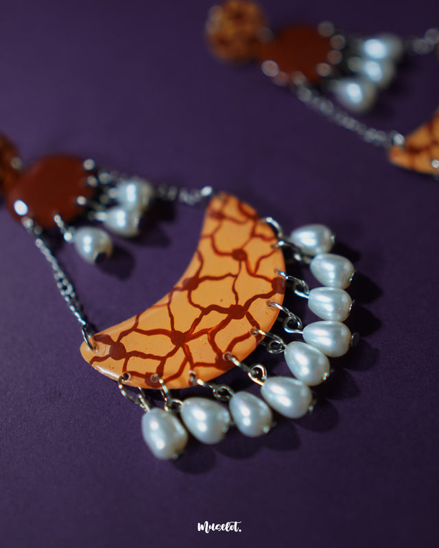 A close-up of the Mittika chandbali earrings showcases the ornate design featuring oxidized silver finish, delicate floral patterns in enamel, and dangling pearl clusters that lend a timeless elegance to this traditional accessory — Muselot.