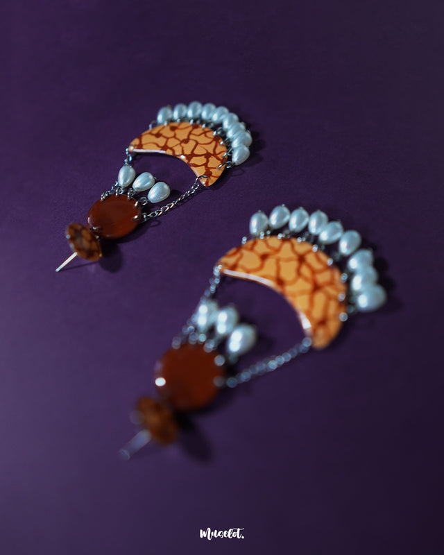 Mittika chandbali earrings captured in a front-facing view, highlighting the intricate crackle pattern in earthy orange tones and glistening pearl drops that dangle elegantly from silver chains — Muselot.
