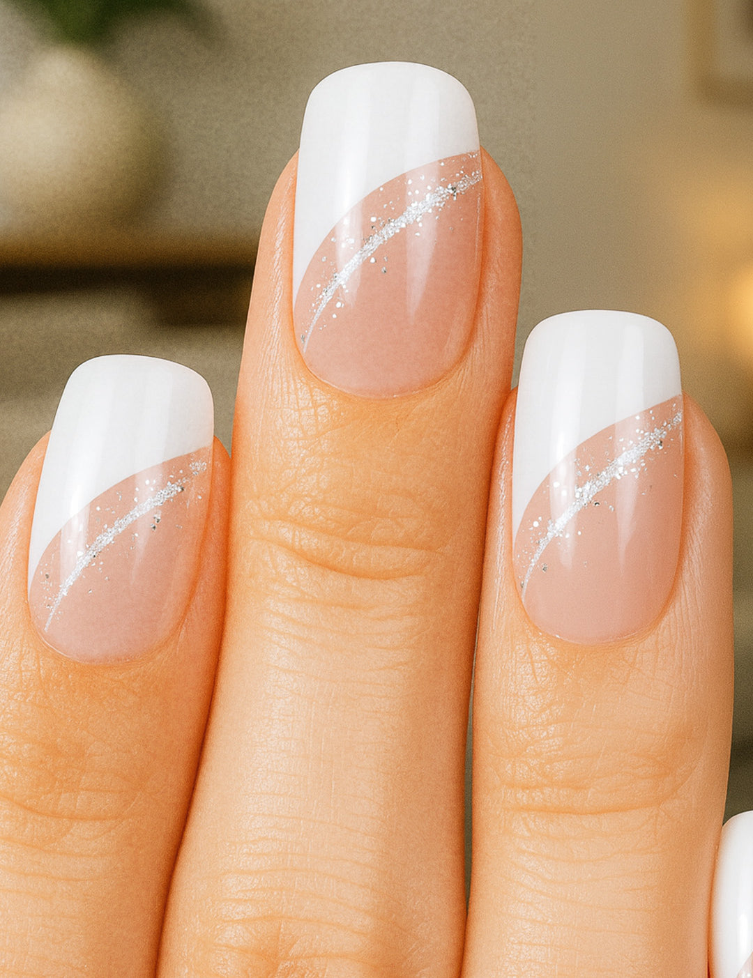 A model’s hand showcasing the Moonlit Wave White French Nail Art from Muselot. The nails feature a modern diagonal French tip in crisp white, highlighted with a fine silver glitter accent line, contrasted against a glossy nude base. The elegant design gives a polished, sophisticated finish perfect for everyday chic or special occasions.