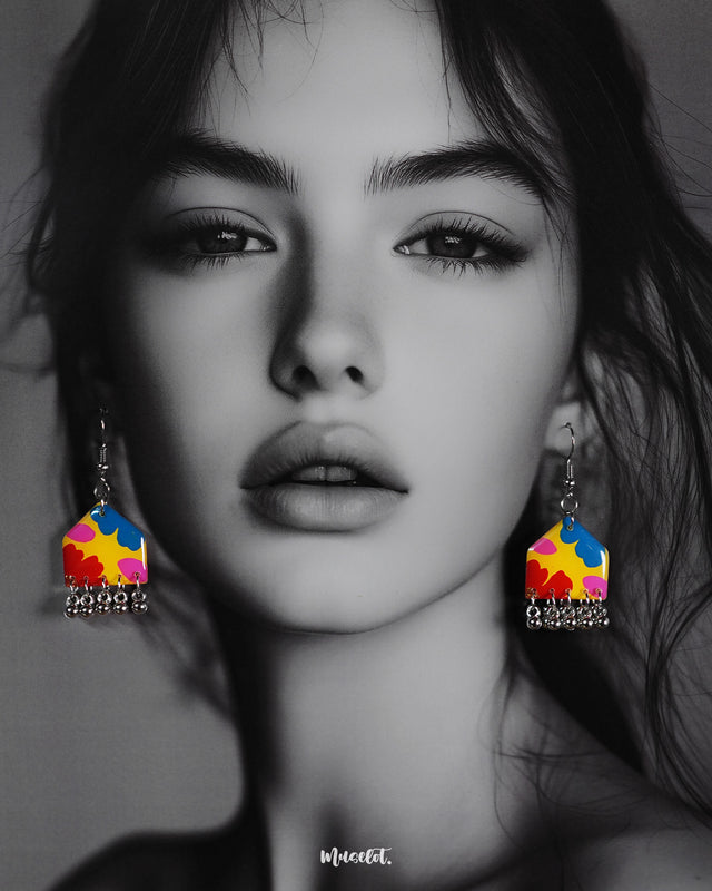 A model wears the multicolor floral earrings, showcasing their vibrant palette of red, blue, yellow, and pink florals with dangling silver ghungroos, adding a playful and colorful charm to the overall look — Muselot.
