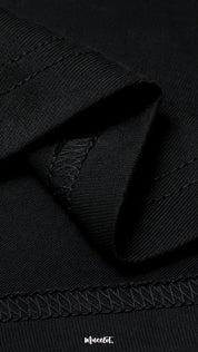 A zoomed-in view of the unisex black t-shirt, highlighting the double seam stitching for added strength, lasting durability, and a neat polished finish—Muselot