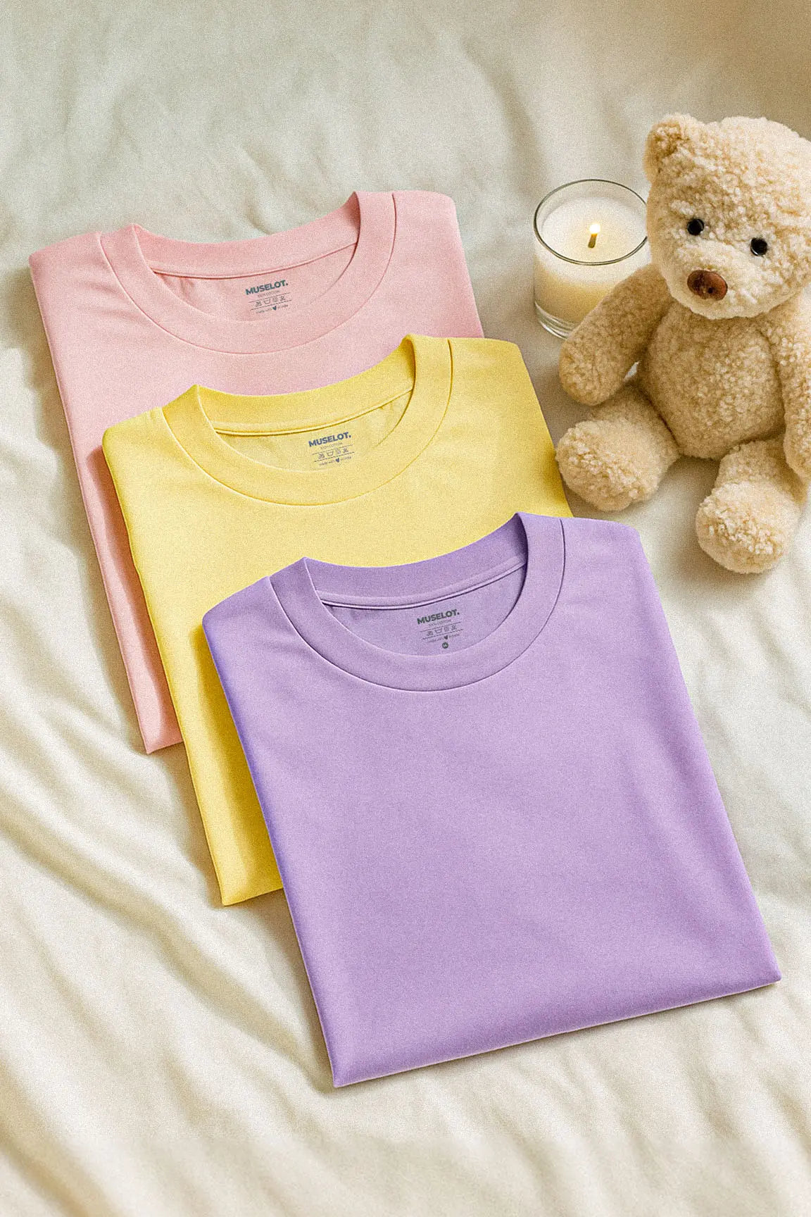 Three soft cotton unisex T-shirts in lilac, butter yellow, and baby pink, laid out neatly against an aesthetic background, showcasing their soothing pastel tones, breathable lightweight fabric, and charming cutecore appeal — Muselot