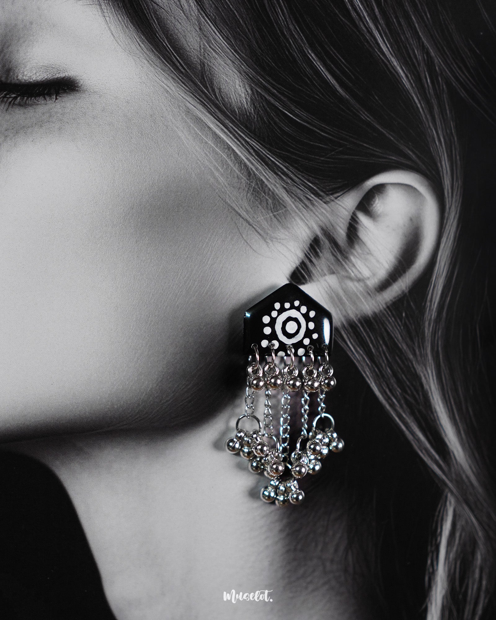 Close-up of model wearing Nazafar black handcrafted earrings, showcasing white circular detailing and cascading silver ghungroo chains – Muselot.