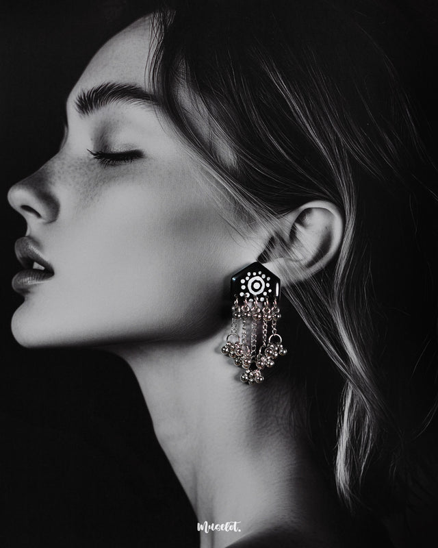 Model wearing Nazafar black handcrafted earrings, featuring white painted motifs and layered silver ghungroo chains for a striking traditional look – Muselot.