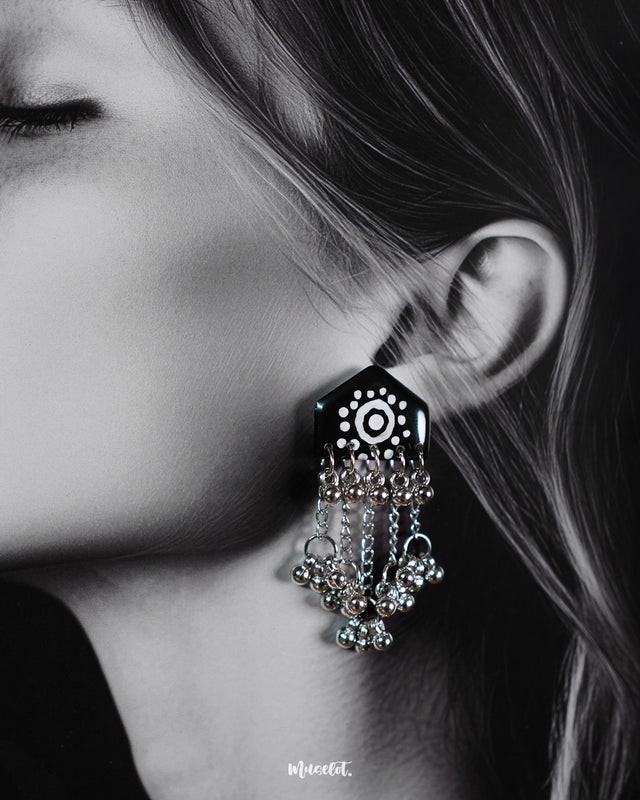 Close-up of model wearing Nazafar black handcrafted earrings, showcasing white circular detailing and cascading silver ghungroo chains – Muselot.