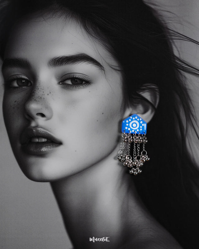 Model wearing Nazafar blue handcrafted earrings, showcasing white painted motifs and cascading silver ghungroo chains for a bold ethnic look – Muselot.