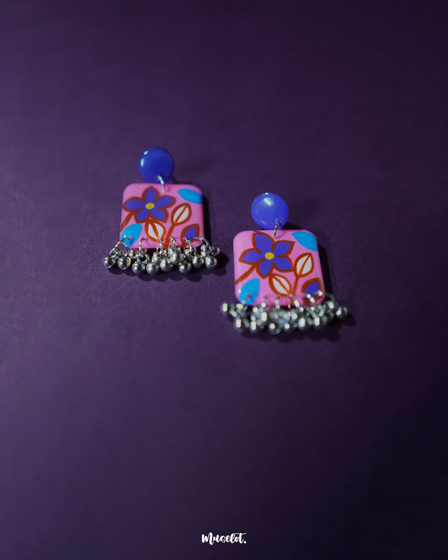 Nazmira handmade floral stud drop earrings, set against a deep purple backdrop, with intricate floral craftsmanship and a graceful drop design that adds a touch of boho elegance to any look — Muselot.