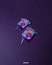 Nazmira handmade floral stud drop earrings, set against a bold purple background, with intricate floral patterns and a delicate drop design that exude a perfect blend of bohemian flair and timeless elegance — Muselot.