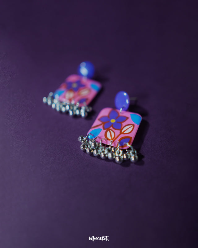 Nazmira handmade floral stud drop earrings, showcased against a rich purple backdrop, with intricate floral studs and a subtle drop that beautifully capture the essence of boho-chic elegance — Muselot.