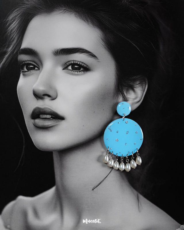 Model wearing the Neerangi pearl earrings, featuring small and large round turquoise blue discs adorned with subtle silver glitter accents and finished with dangling white pearl-like beads, emphasizing their bright, graceful, and festive look – Muselot.
