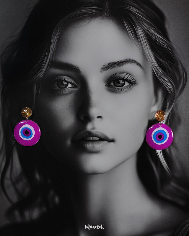 A model flaunting the Nigaahbaan stud earrings, where the golden glitter tops meet bold concentric circles of blue, white, and black on a vivid magenta base—an eye-catching fusion of charm and tradition — Muselot.