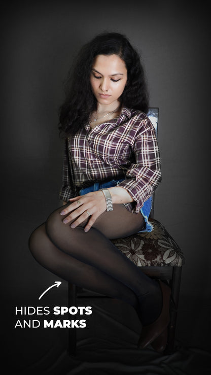 A woman sitting on a chair with her hand on her thigh as she looks at her tights, wearing black no fur transparent stockings, showcasing the modish perfect look-Muselot