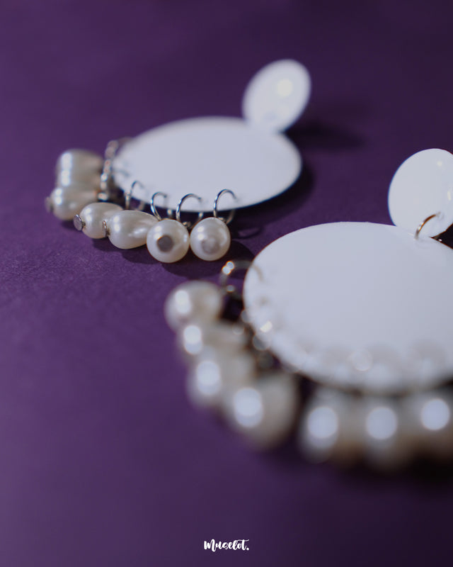 A zoom in shot of Noor white drop earrings with crescent-shaped design and dangling pearl beads, captured from a side angle to highlight their handcrafted charm and showcase the subtle movement and elegance — Muselot.