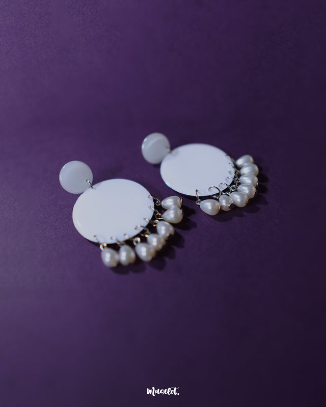 A pair of Noor white drop earrings laid flat, showcasing their crescent shape adorned with intricate pearl-like beads and fine metallic detailing that highlights their traditional charm and artisanal craftsmanship — Muselot.