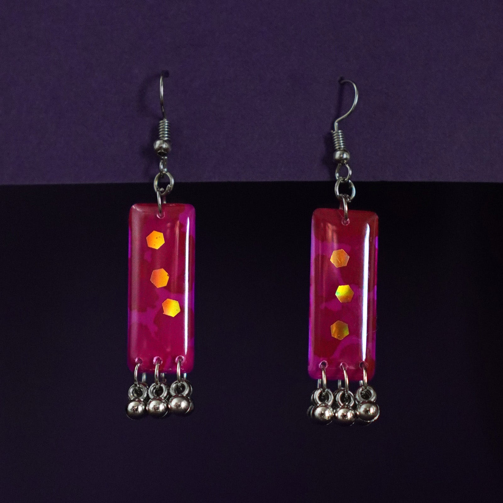 Noorasa pink drop earrings placed against a purple-toned backdrop, highlighting their dainty floral design and soft feminine elegance – Muselot